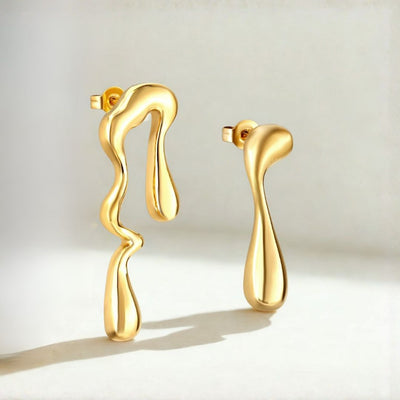 Gold earrings with a wavy design on a light background